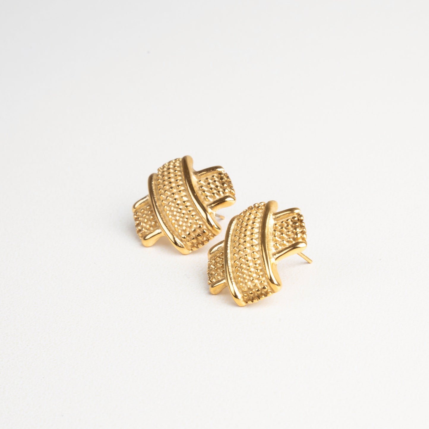 Detalle cercano de la textura en aretes tipo tacha dorados, estilo sofisticado y actual