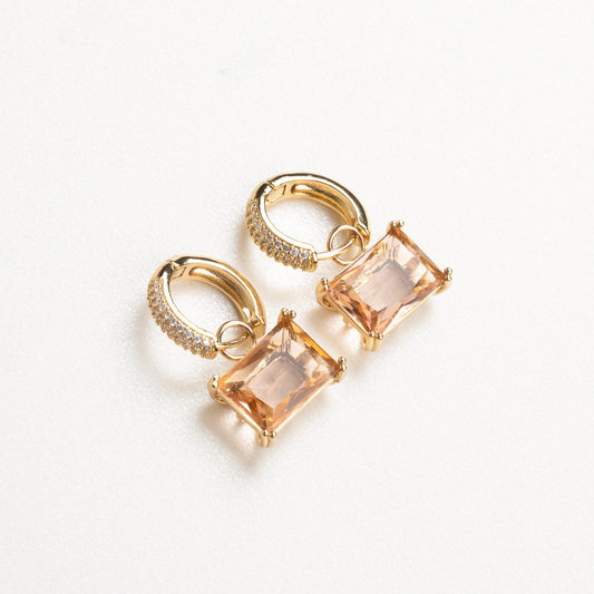 Aretes arracadas elegantes con una zirconia cuadrada colgando, combinando la forma clásica de las arracadas con el brillo moderno de una piedra cuadrada, perfecta para un look sofisticado y llamativo.